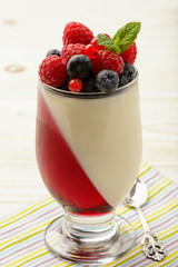 Delicious dessert - panna cotta with berry jelly and berries.