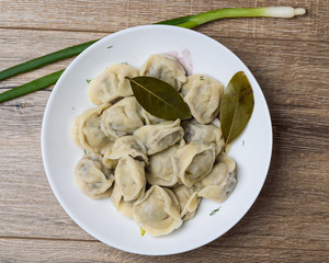 plate of traditional Russian pelmeni on wooden table