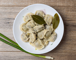 plate of traditional Russian pelmeni on wooden table