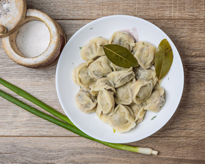 plate of traditional Russian pelmeni on wooden table