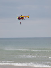 A red and yellow helicopter with rescuers