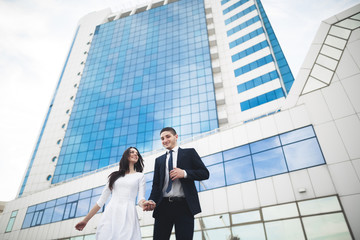 Stylish loving couple kissing and hugging near modern building