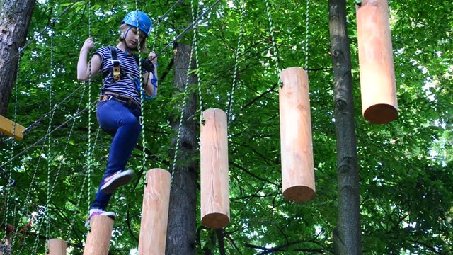 The girl the teenager overcomes obstacles between trees at height. Rope town.