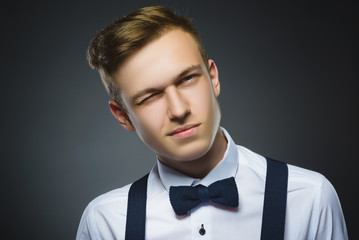 Portrait of boy winking over gray background. Positive human emotion facial expression body language