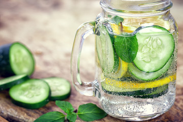 Detox Infused water with cucumber and lemon on wooden background