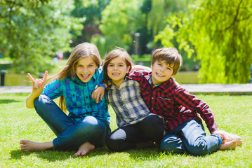 Fototapeta premium Smiling kids having fun at grass. Children playing outdoors in summer. teenagers communicate outdoor