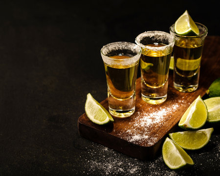 Mexican Gold Tequila with lime and salt on wooden table, selective focus. Copyspace.