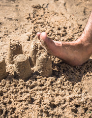 male leg attacks the sandy town on the beach