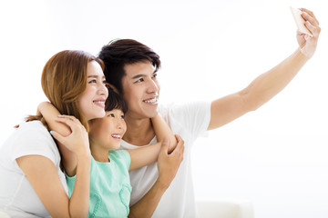 Obraz na płótnie Canvas Happy young family taking selfies on sofa