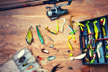 Fishing baits and rod isolated on wooden background