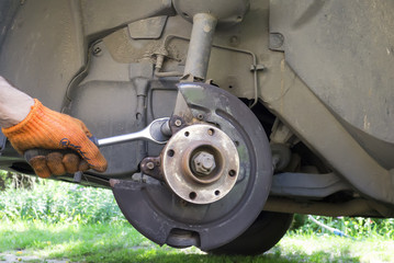 Man unscrew bolt on the brake system of his car. Close up view.