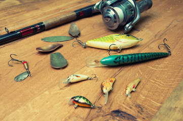 Fishing baits and rod isolated on wooden background