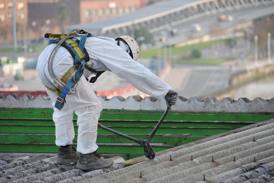 trabajador de amianto desmonta tejado con ciudad de Bilbao al fondo