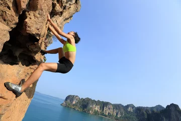 Gordijnen young woman rock climber climbing at seaside mountain cliff © lzf