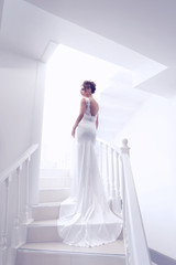 young beautiful bride, back view, posing on stairs indoor