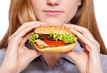It is so delicious.  Attractive young woman eat hamburger over white background.