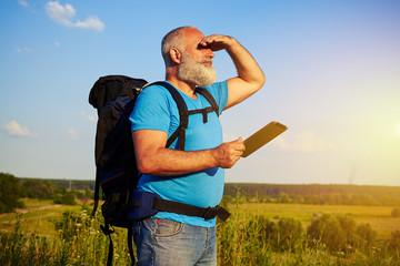 Aged tourist with rucksack looking into the distance his hand co