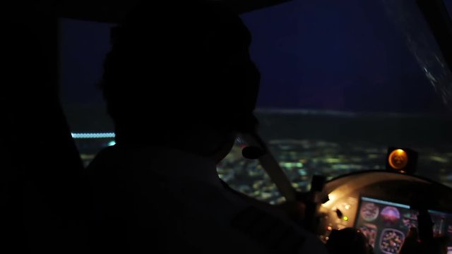 Pilot in headset maneuvering airplane above evening city, responsible job