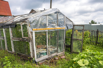 Old greenhouse for growing vegetables made from discarded materials and old window frames