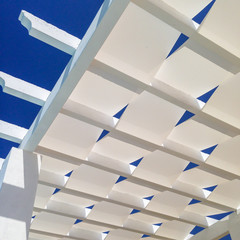 The white material weave of the roof of a pergola. Looking up at a blue summer, Spanish sky. the...