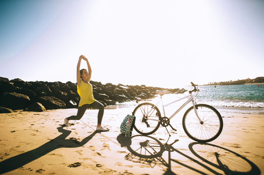 Young women is engaged in yoga on sunset with bike
