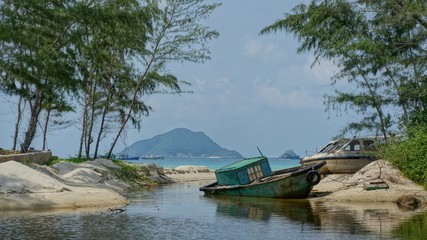 Boat in lagoon. An old obsolete blue boat laying on the beach shore of a lagoon. Tropical scene looking like paradise taken on the Vietnamese island Con Dao.