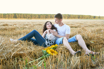 happy young couple sit in wheaten field at evening, romantic people concept, beautiful landscape, summer season