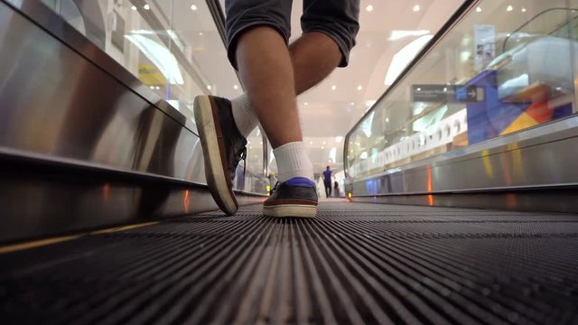 Rear view of male legs on escalator at airport