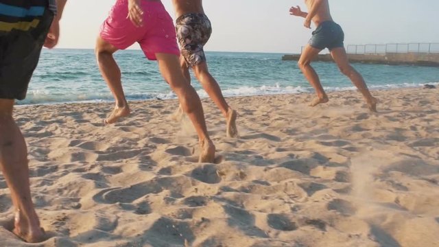 Group of friends running and jumping in the sea during sunset, slow motion