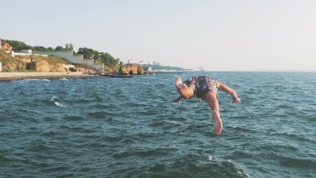 Guy Running And Jumping Off Sea Pier In The Water, Slow Motion