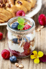 Glass jar with fruits and whipped cream.