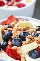 Bowl of yogurt with muesli and fresh fruits: strawberries, blueb