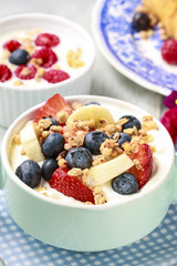 Bowl of yogurt with muesli and fresh fruits: strawberries, blueb