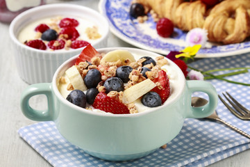 Bowl of yogurt with muesli and fresh fruits: strawberries, blueb