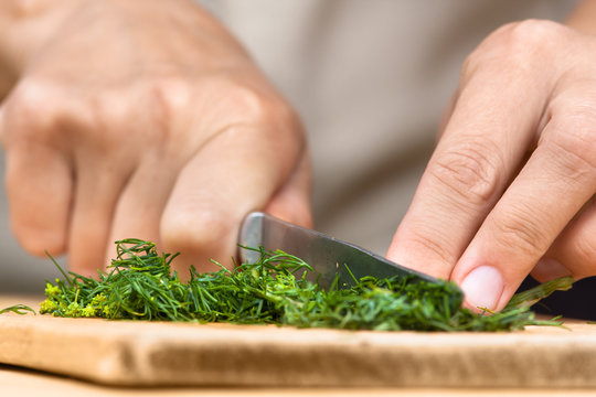 hands chopping fresh dill on the cutting board