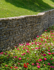 Flowers, green grass and retaining wall gray brick
