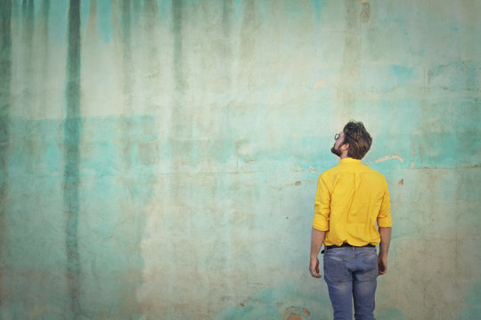 Man with yellow shirt looking at the wall