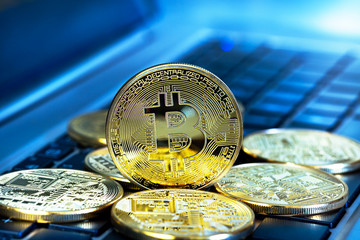 Photo Golden Bitcoins (new virtual money ) close-up on a blue background with a computer keyboard.