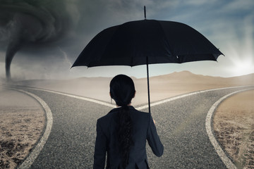 Worker with umbrella looking at two roads
