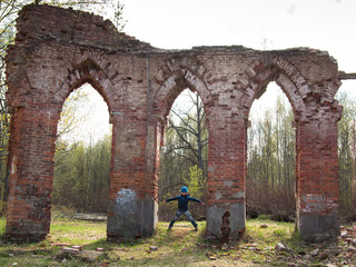 A boy stands near the ruins on forest background