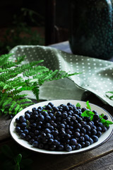 Plate with bilberry on wooden table