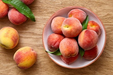 Fototapeta na wymiar Ripe peaches in a bowl on wooden background