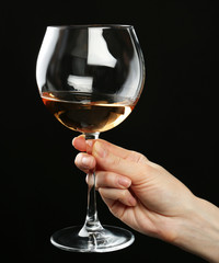 Female hand holding glass of champagne on black background