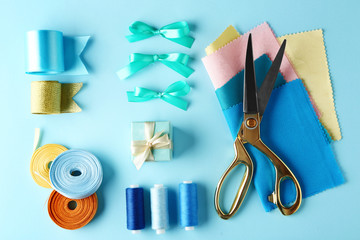 Sewing creative accessories on blue background, top view