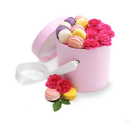 Tasty macaroons and roses in box on light background