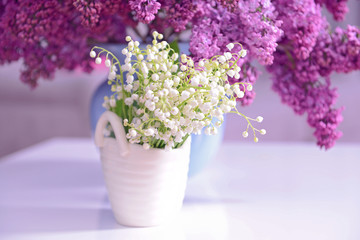 Lilac and may-lily bouquets on white table