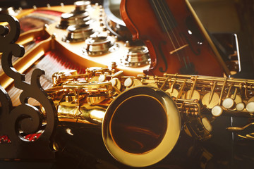 Fototapeta premium Violin and saxophone lying on piano, close up