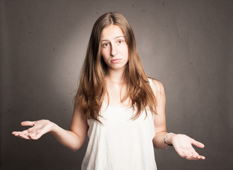 young woman shrugging shoulders on a gray background