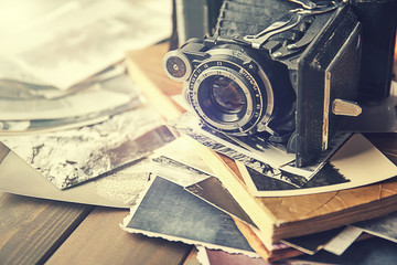 Album with vintage photos and camera on wooden background
