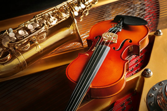 Violin and saxophone lying on piano, close up